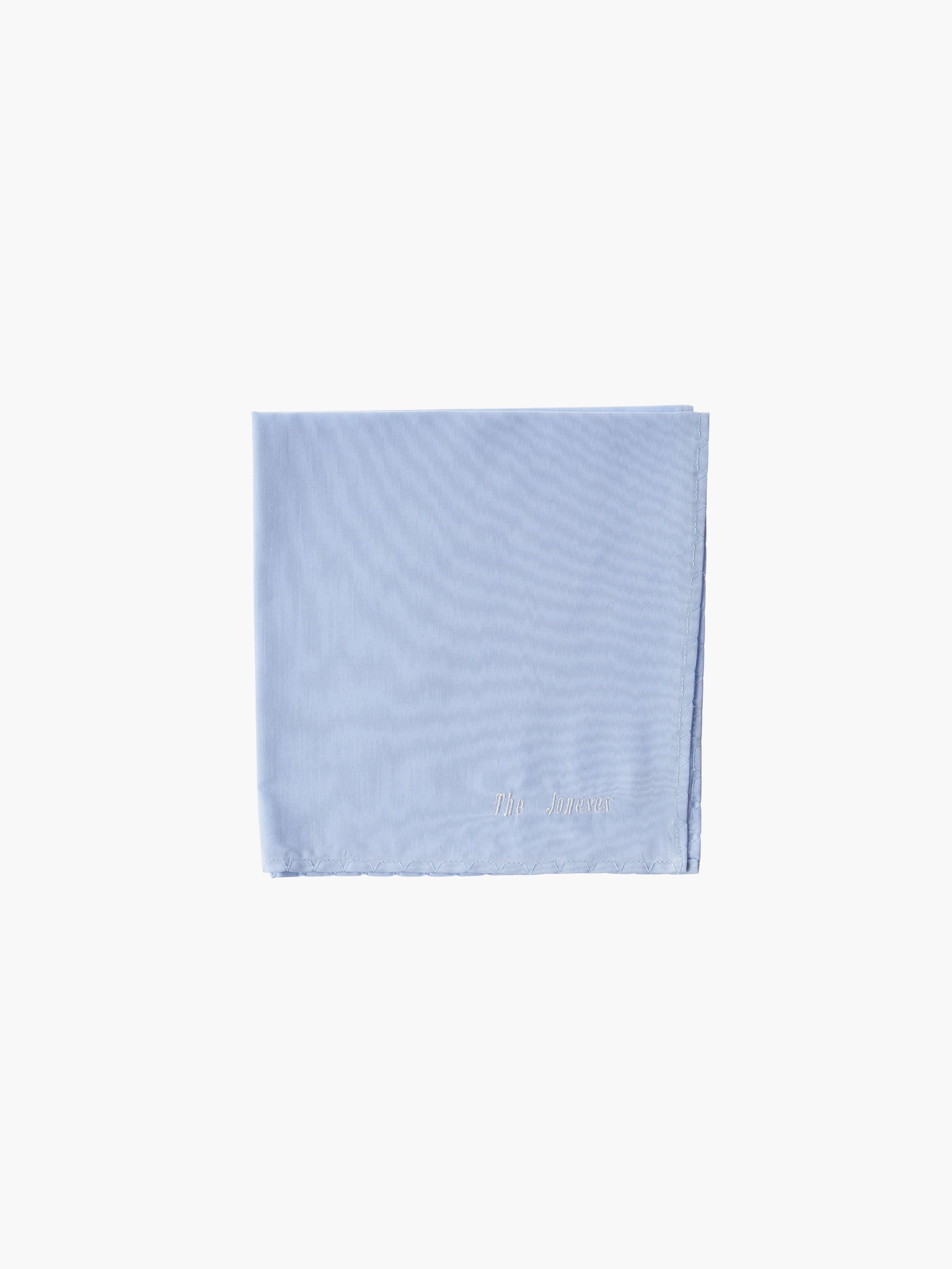 A blue cotton embroidered square handkerchief, embroidered with "The Joneses" in white.
