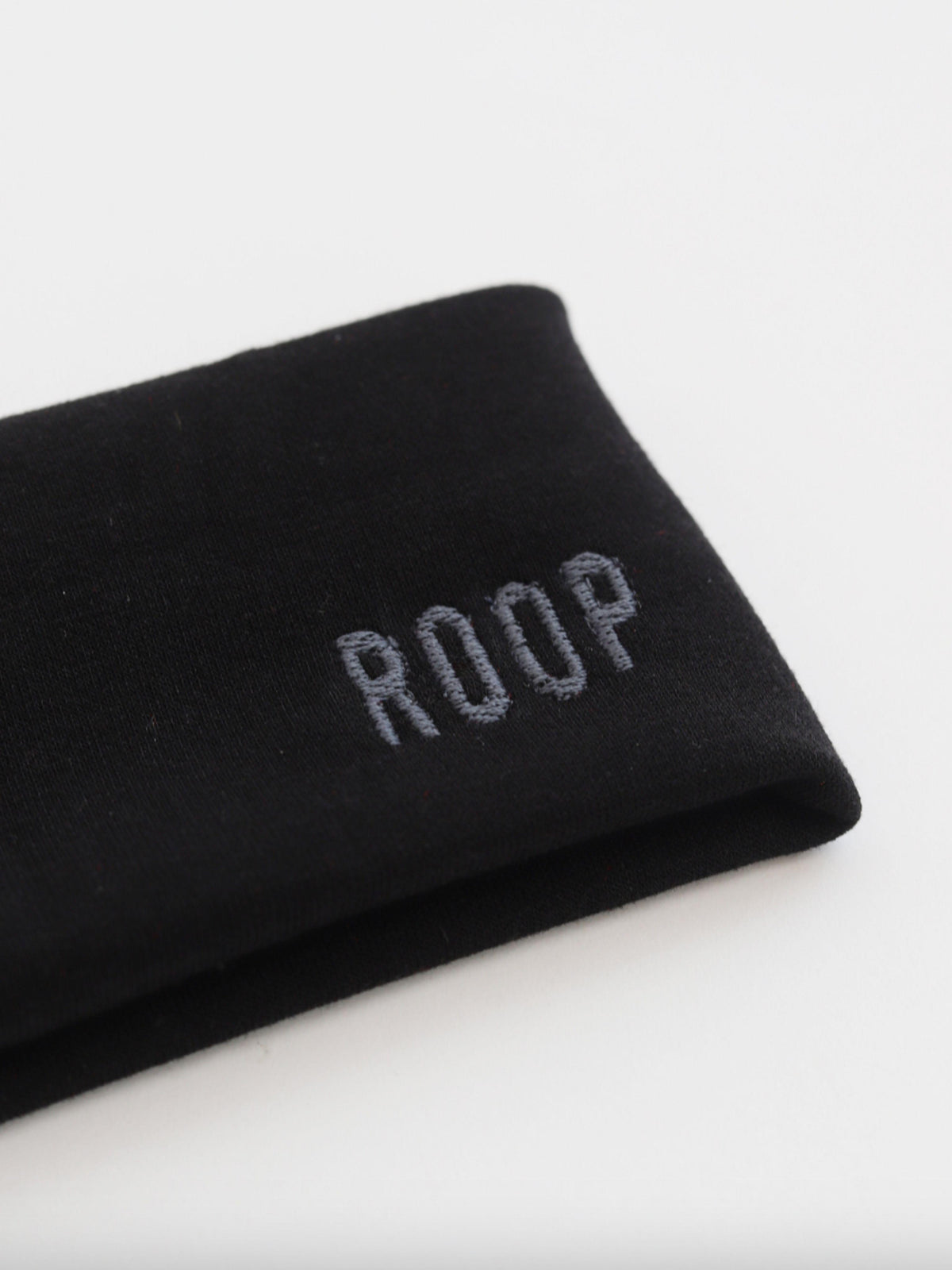 Black stretch headband with 'ROOP' embroidery on a white background
