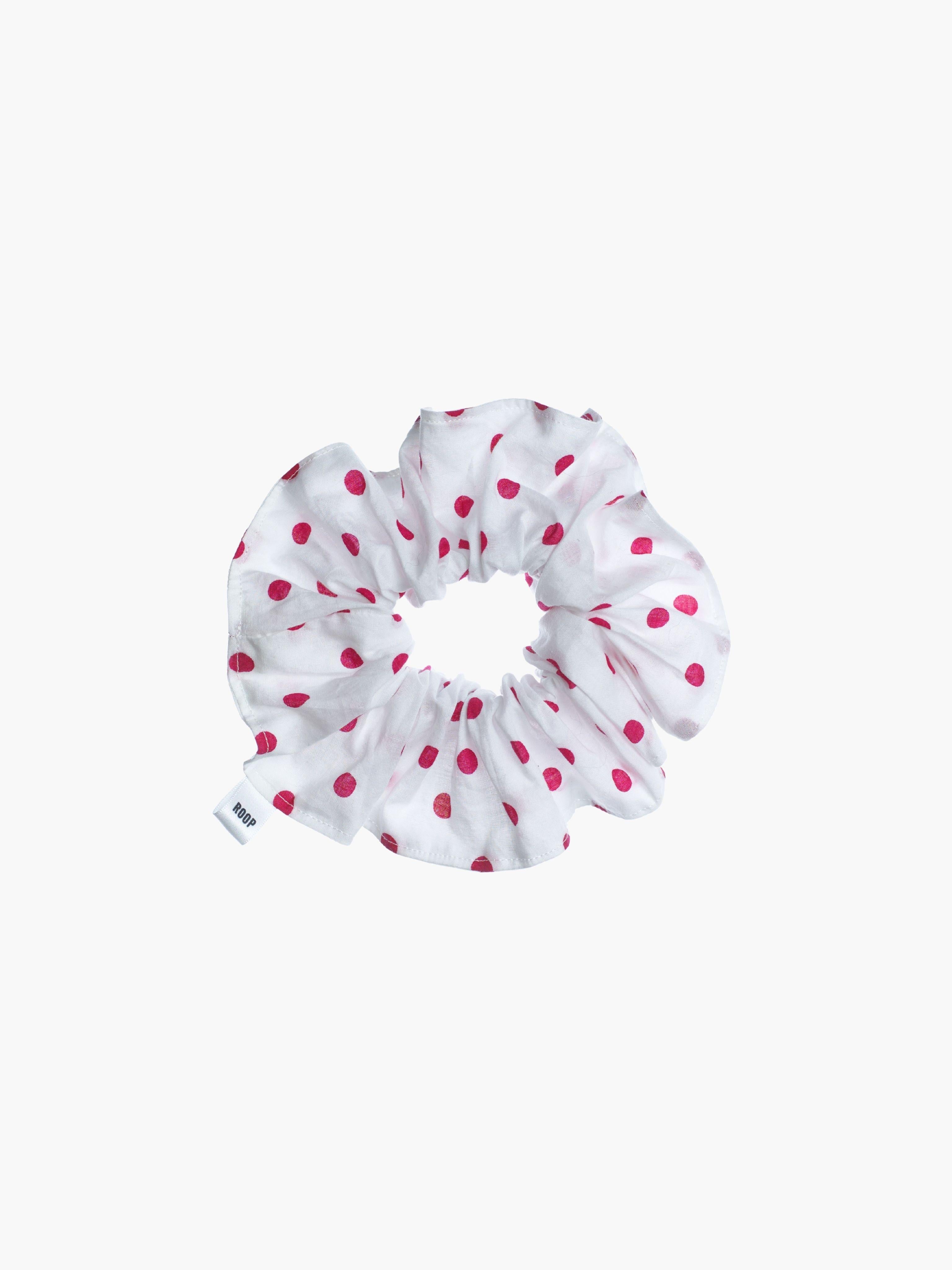 White scrunchie with pink polka dots on a white background