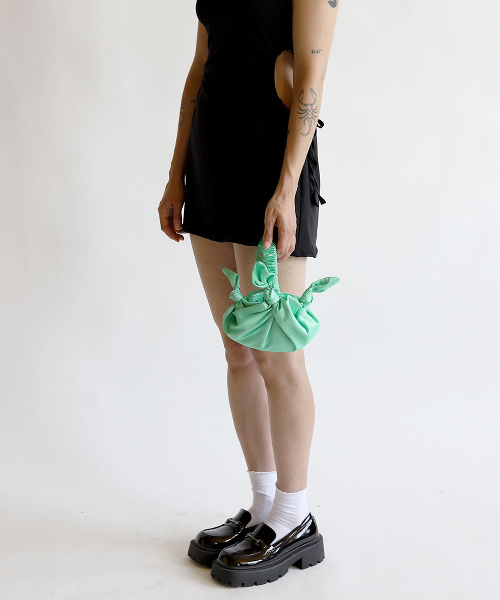 Model wearing black dress holding baby furoshiki handbag in deadstock mint green taffeta