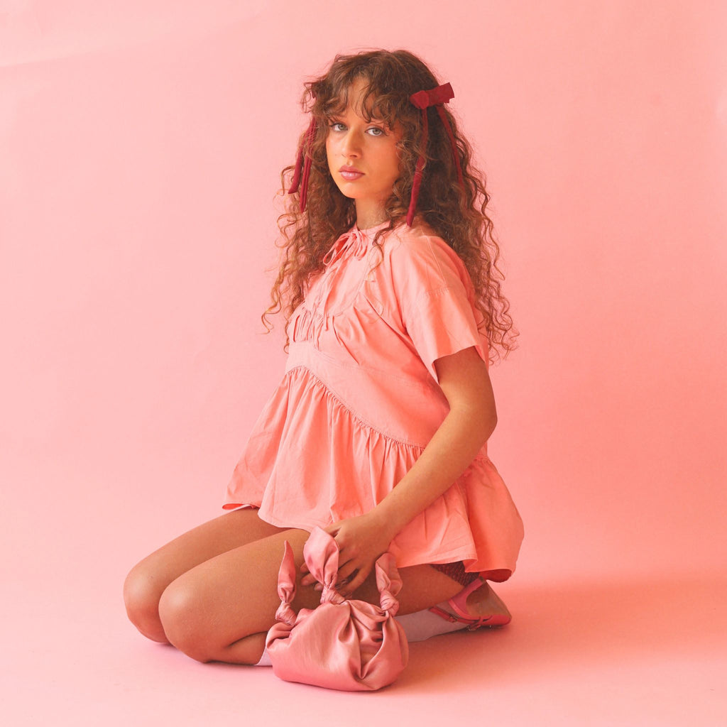 Woman in a pink outfit with a pink bag on a pink background