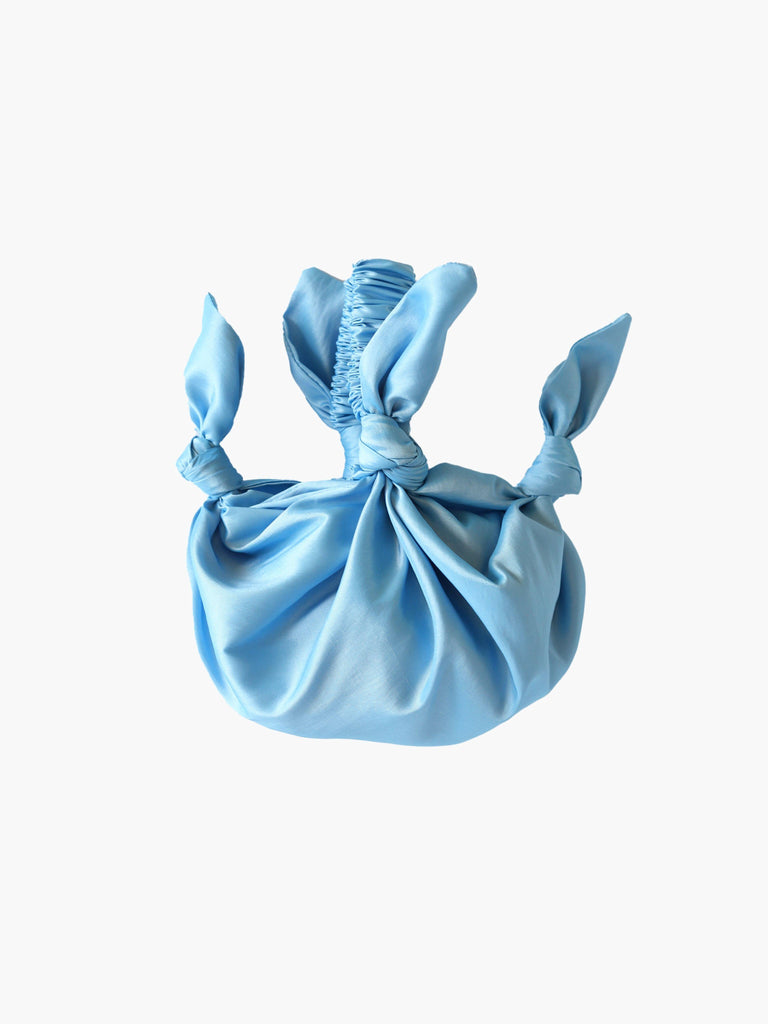 light blue taffeta knotted handbag on white background