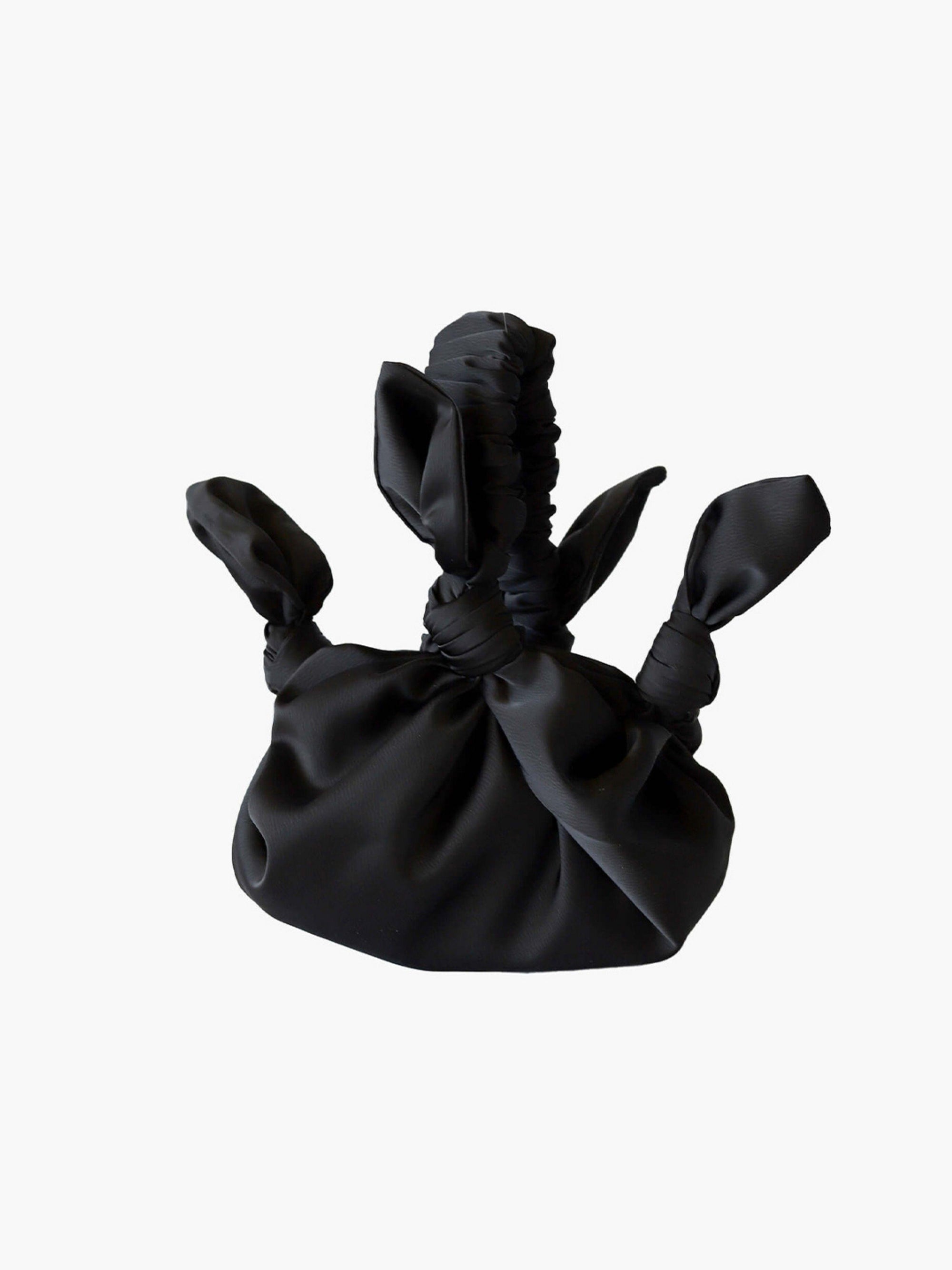Black satin knotted fabric bag on a white background