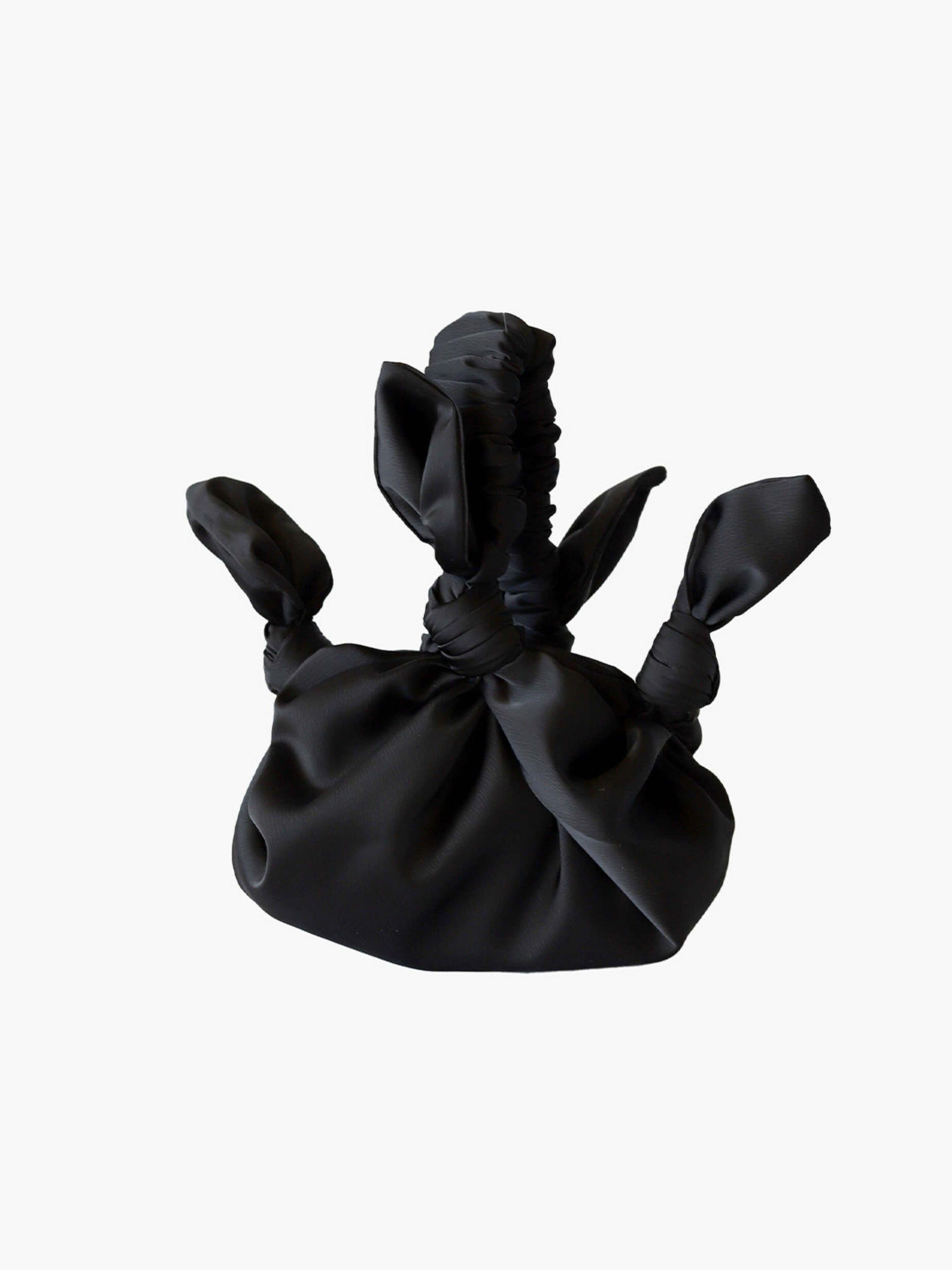 Black satin knotted fabric bag on a white background