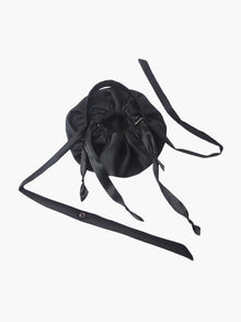 Black satin puffball drawstring bag with a long straps, set on a white background
