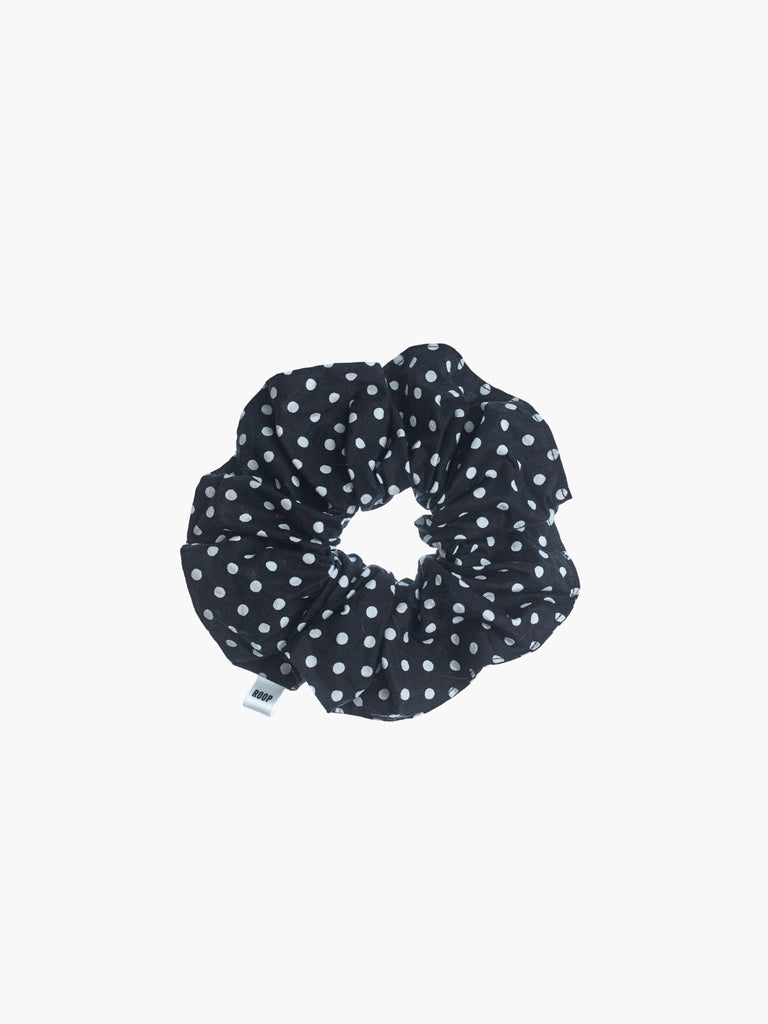 Black scrunchie with white polka dots on a white background