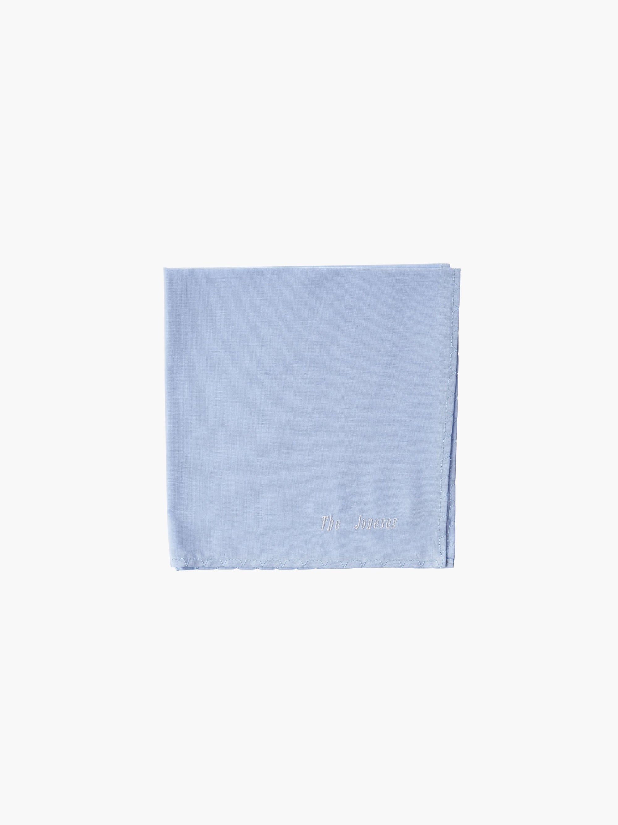 A blue cotton embroidered square handkerchief, embroidered with "The Joneses" in white. 