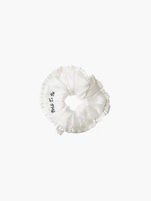 Ivory ruffled scrunchie with black embroidery that reads 'bride to be' on a white background