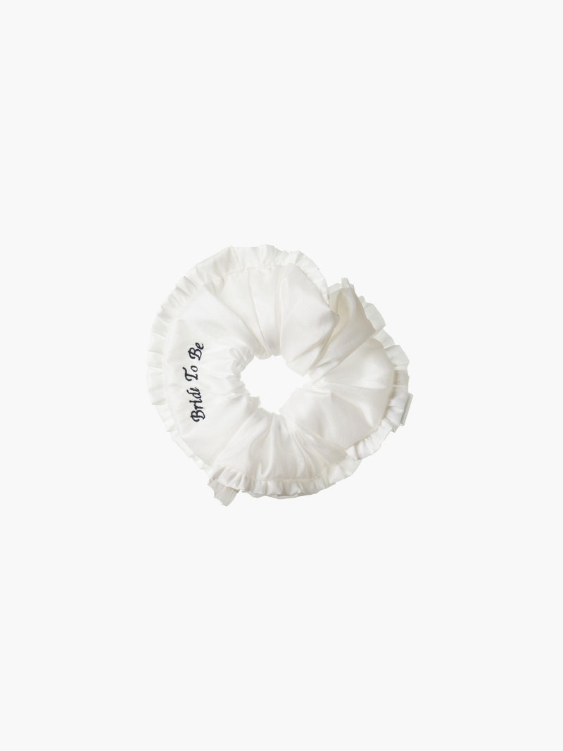 Ivory ruffled scrunchie with black embroidery that reads 'bride to be' on a white background