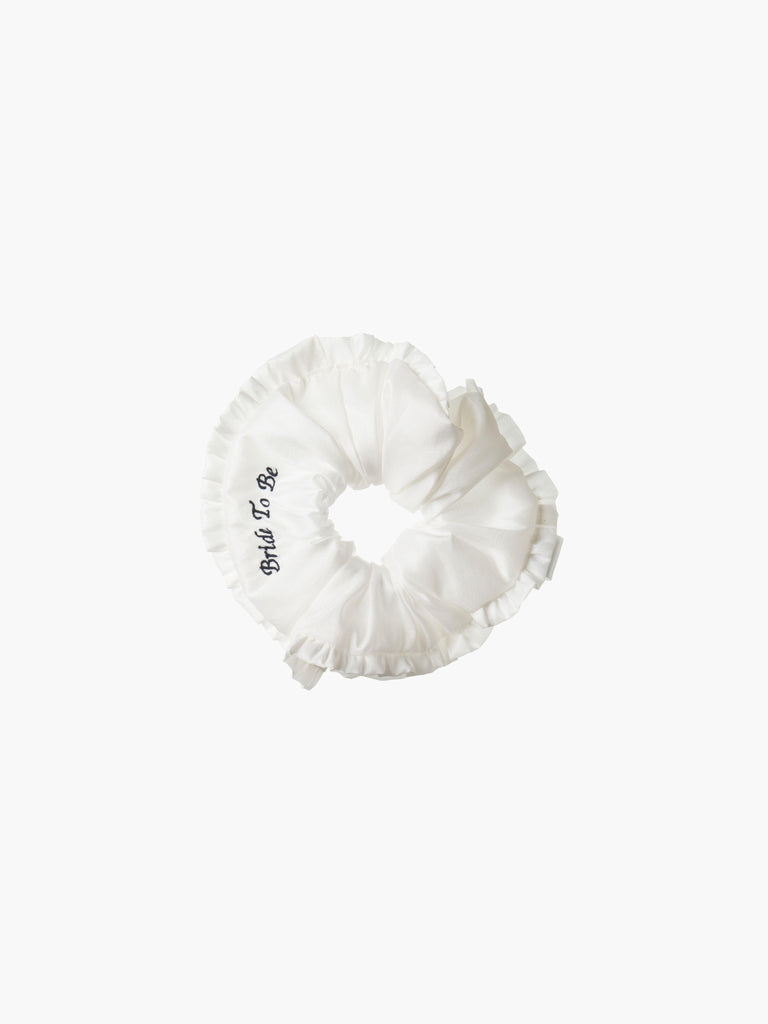 Ivory ruffled scrunchie with black embroidery that reads 'bride to be' on a white background
