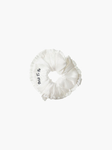 Ivory ruffled scrunchie with black embroidery that reads 'bride to be' on a white background