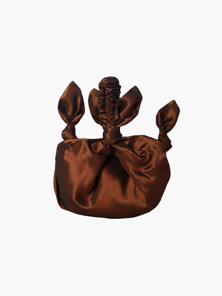 bronze knotted taffeta handbag on a white background