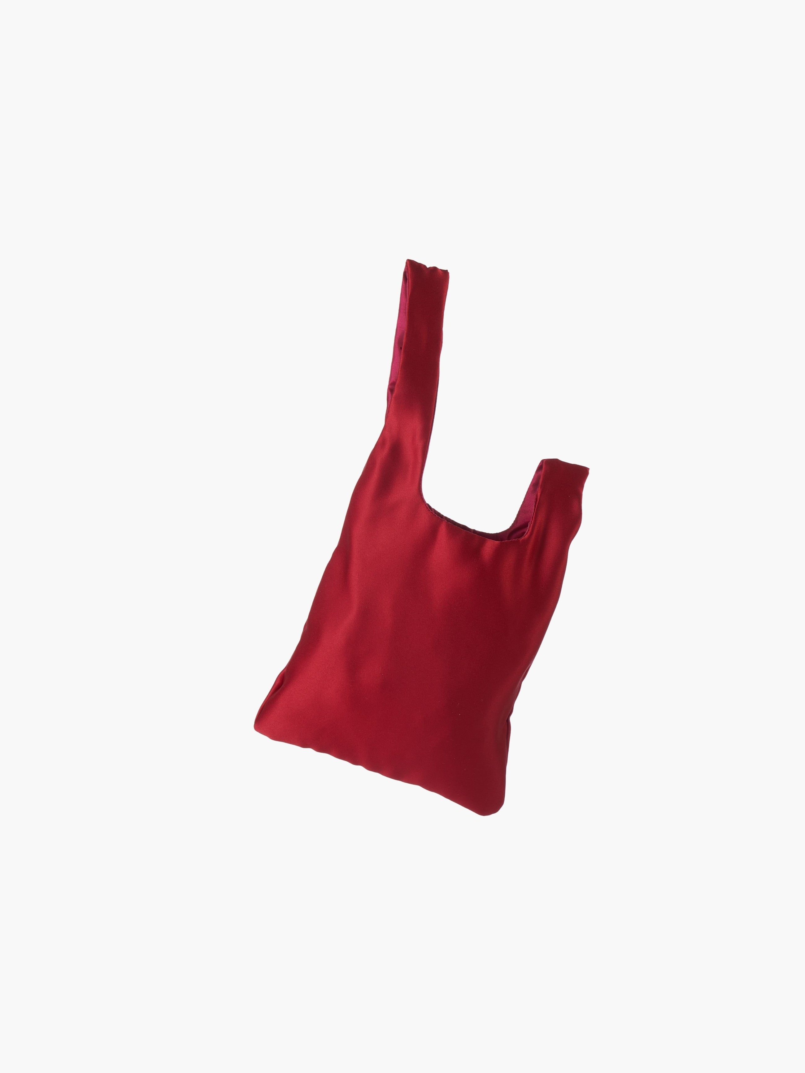 Burgundy satin knot bag against a plain white background. The elegant bag has a twisted handle and sleek, glossy fabric, exuding a chic, minimalist style.