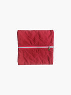 A quilted burgundy cotton zipper pouch, the zip has a heart charm on it. Set on a white background.