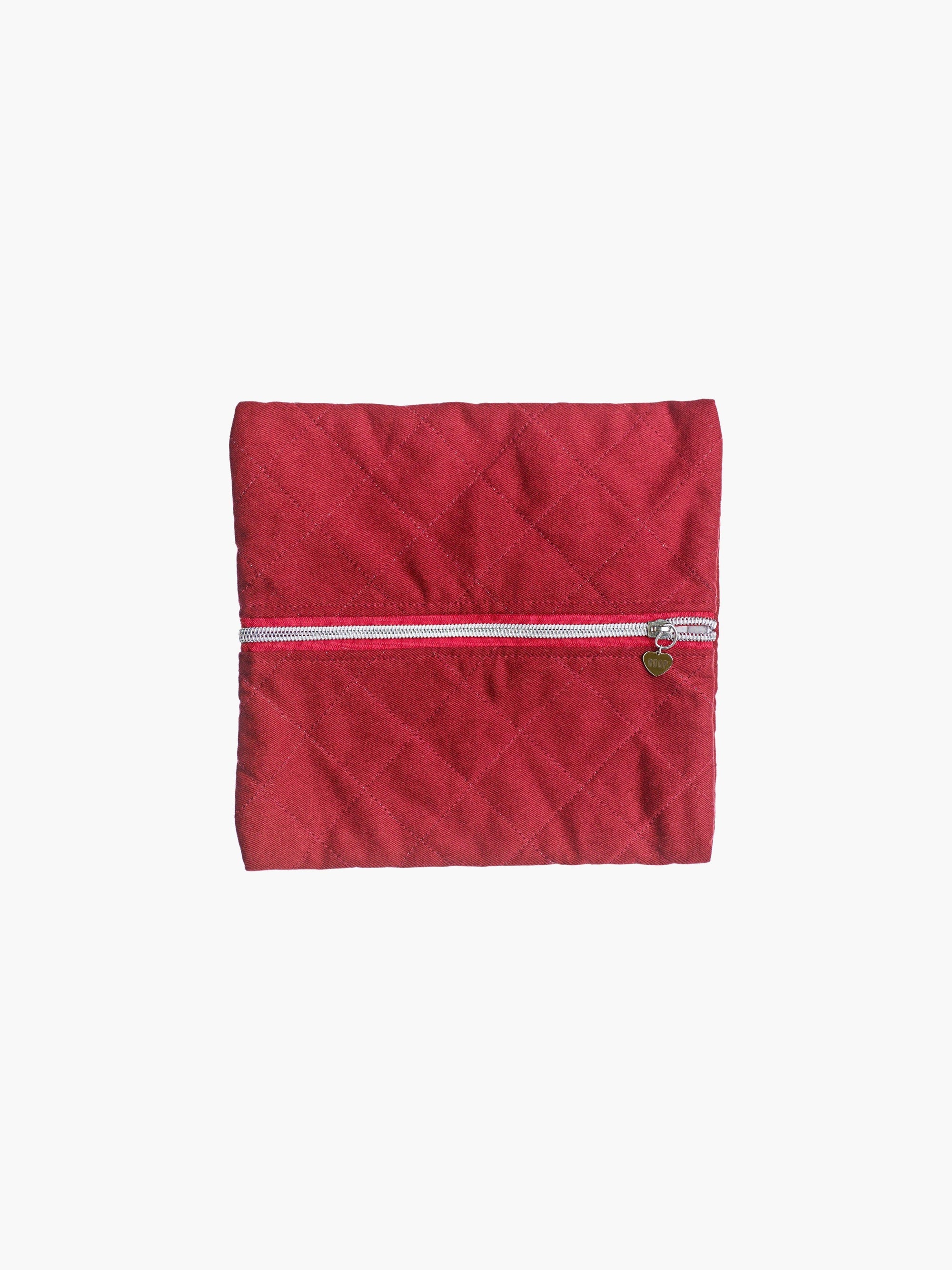 A quilted burgundy cotton zipper pouch, the zip has a heart charm on it. Set on a white background.