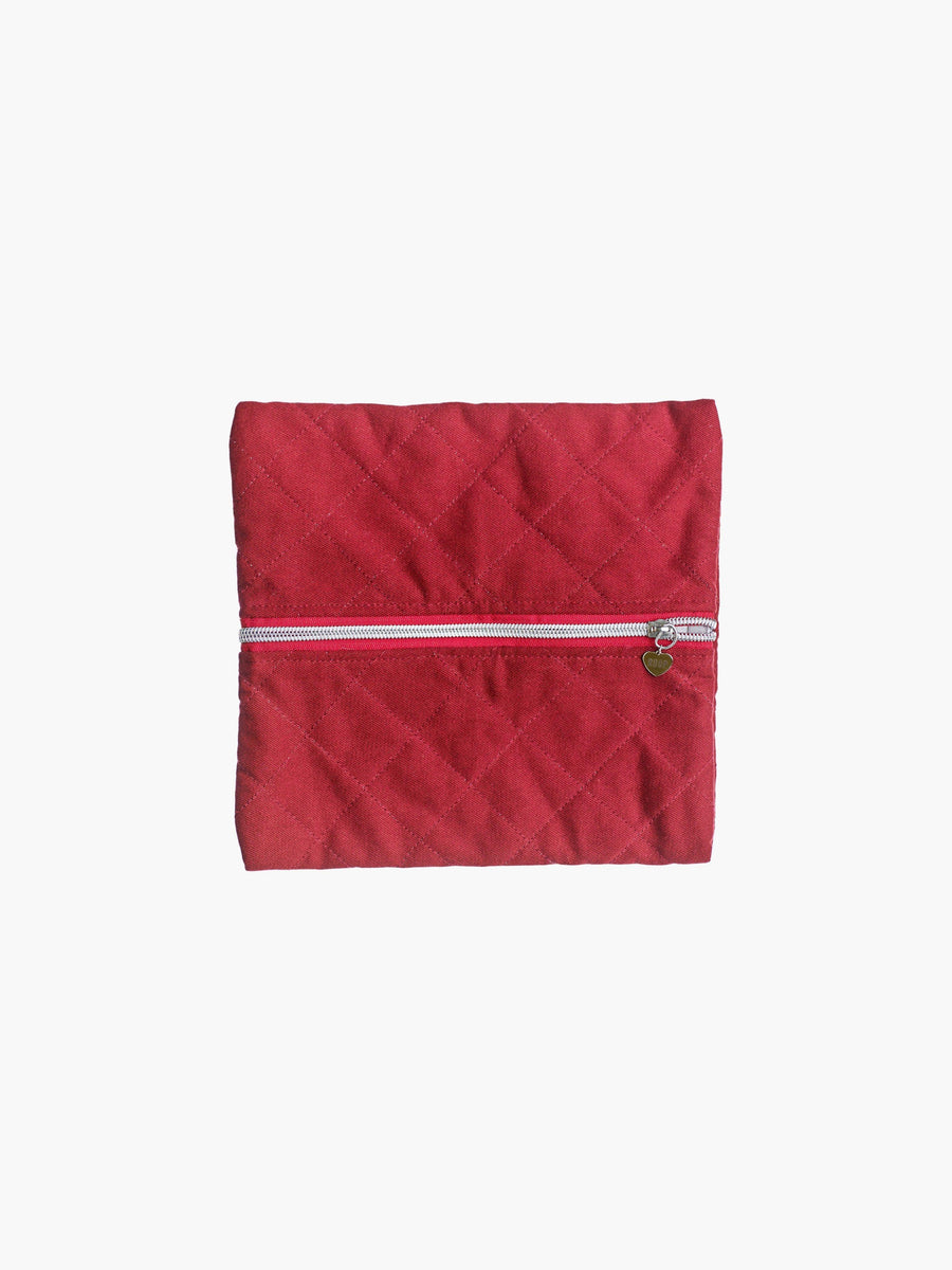A quilted burgundy cotton zipper pouch, the zip has a heart charm on it. Set on a white background.