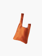 Burnt orange satin knot bag against a plain white background. The elegant bag has a twisted handle and sleek, glossy fabric, exuding a chic, minimalist style.