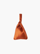 Burnt orange satin knot bag against a plain white background. The elegant bag has a twisted handle and sleek, glossy fabric, exuding a chic, minimalist style.