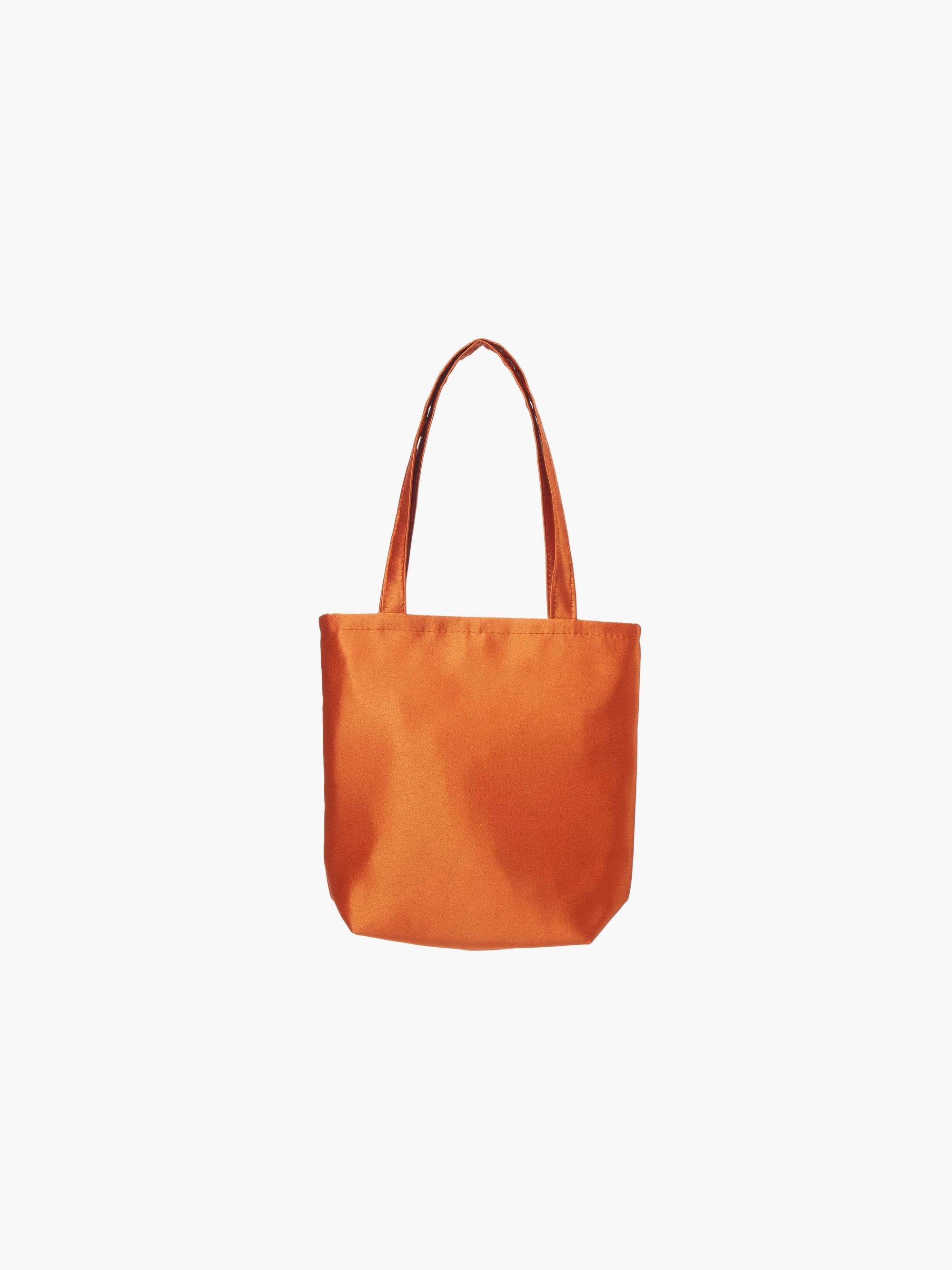 A burnt orange satin tote bag with. It features matching handles, set against a plain white background.