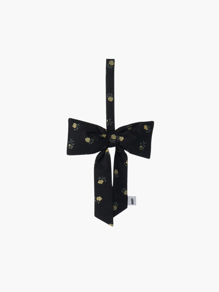 A black and yellow floral padded fabric bow featuring a loop for hanging. The bow exudes a playful and decorative feel.