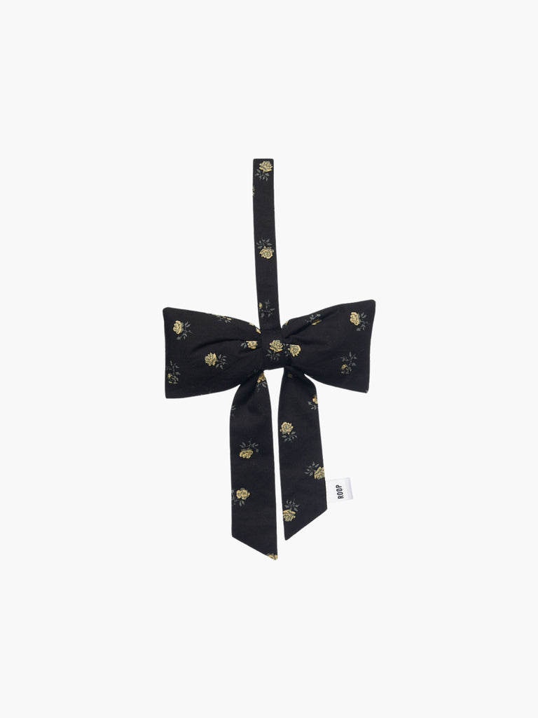 A black and yellow floral padded fabric bow featuring a loop for hanging. The bow exudes a playful and decorative feel.