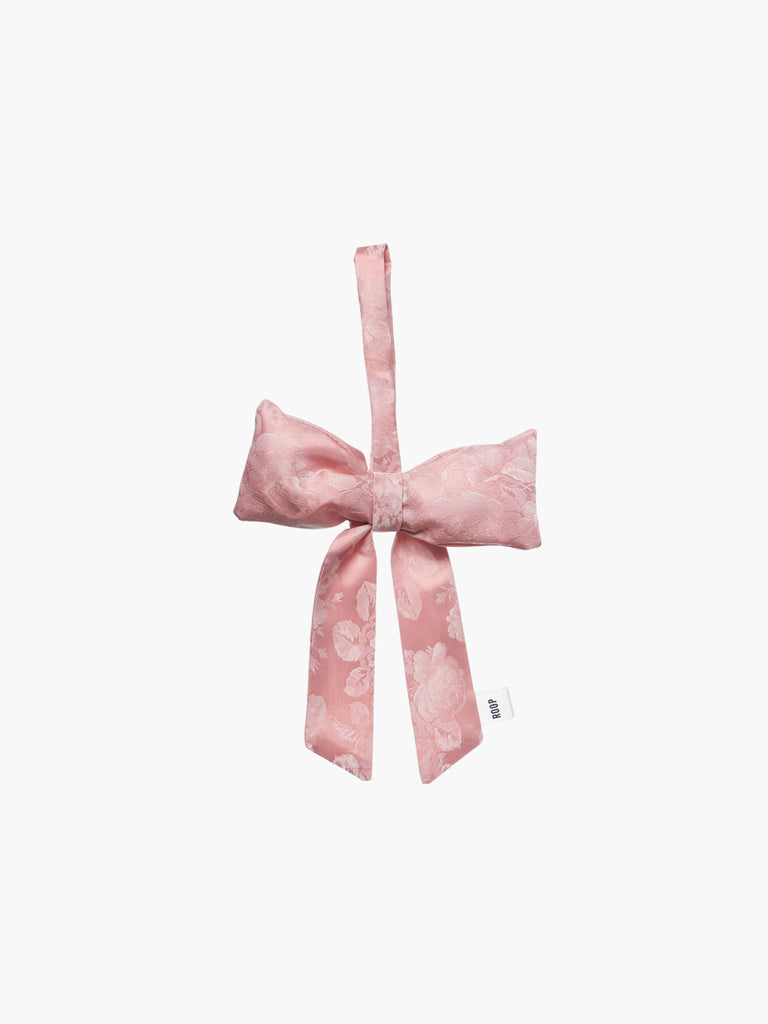 Pink floral satin bow-shaped decorative item on a white background