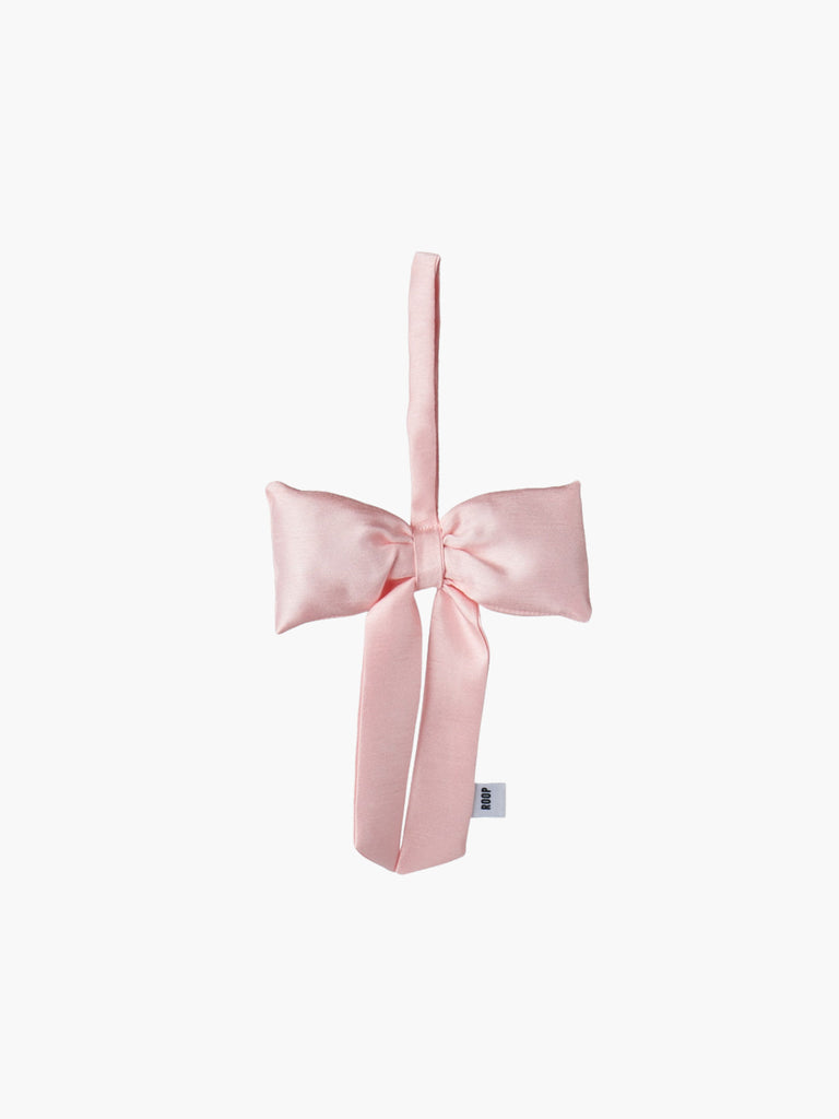 A pink padded fabric bow featuring a loop for hanging. The bow exudes a playful and decorative feel.