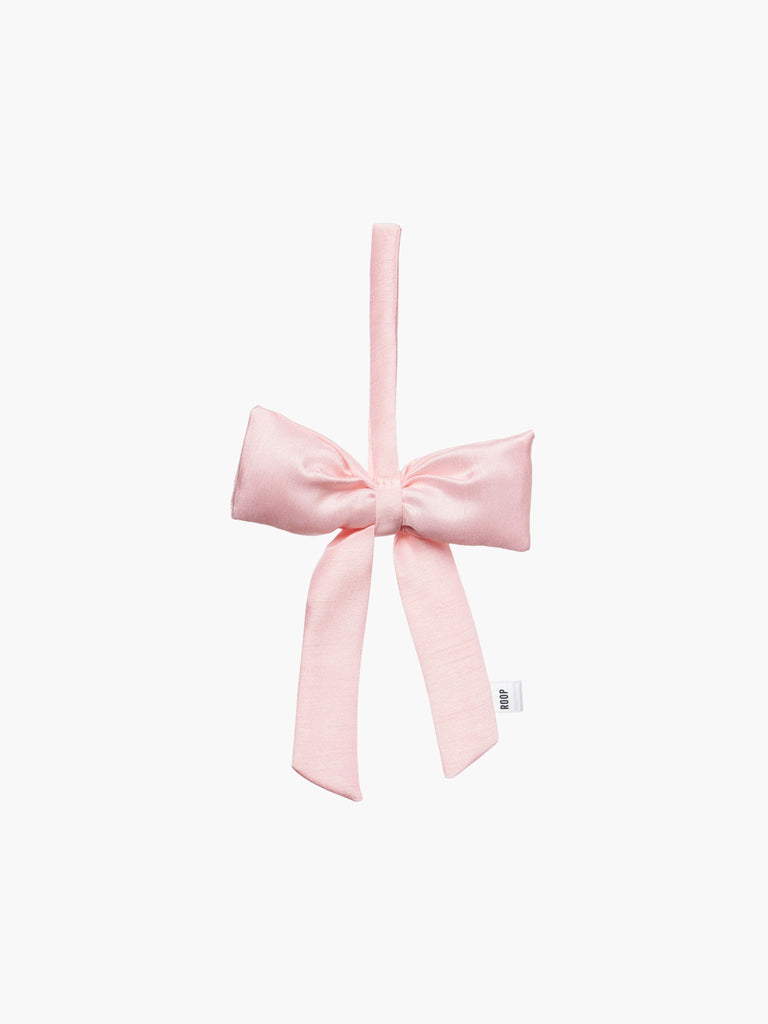 A pink padded fabric bow featuring a loop for hanging. The bow exudes a playful and decorative feel.