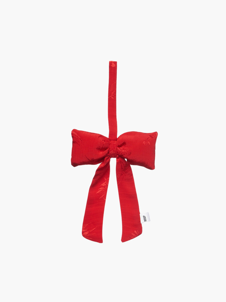 A red floral satin padded fabric bow featuring a loop for hanging. The bow exudes a playful and decorative feel.