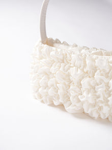 Close up of an ivory satin textured ruched front handbag. Set on a white background.