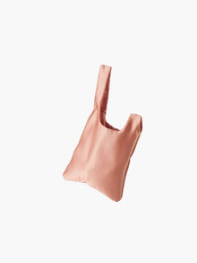 Rose gold satin knot bag against a plain white background. The elegant bag has a twisted handle and sleek, glossy fabric, exuding a chic, minimalist style.