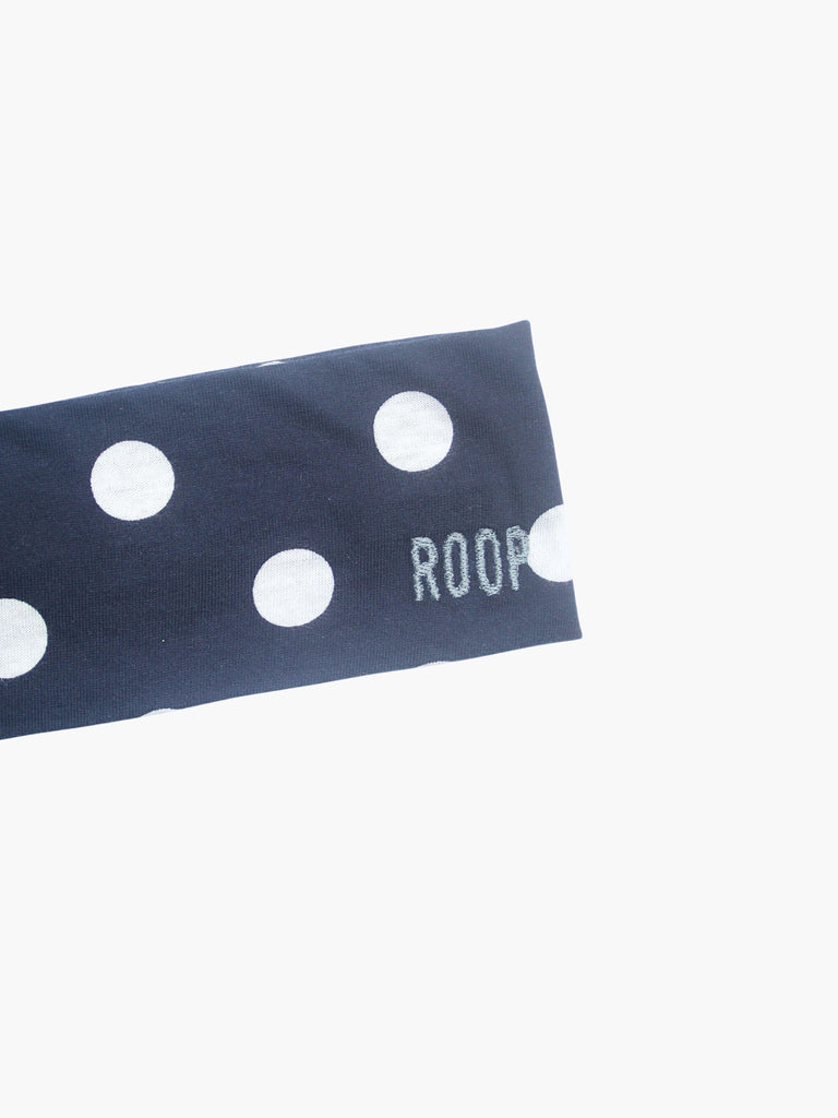 Navy blue stretch headband with white polka dots and 'ROOP' embroidery on a white background