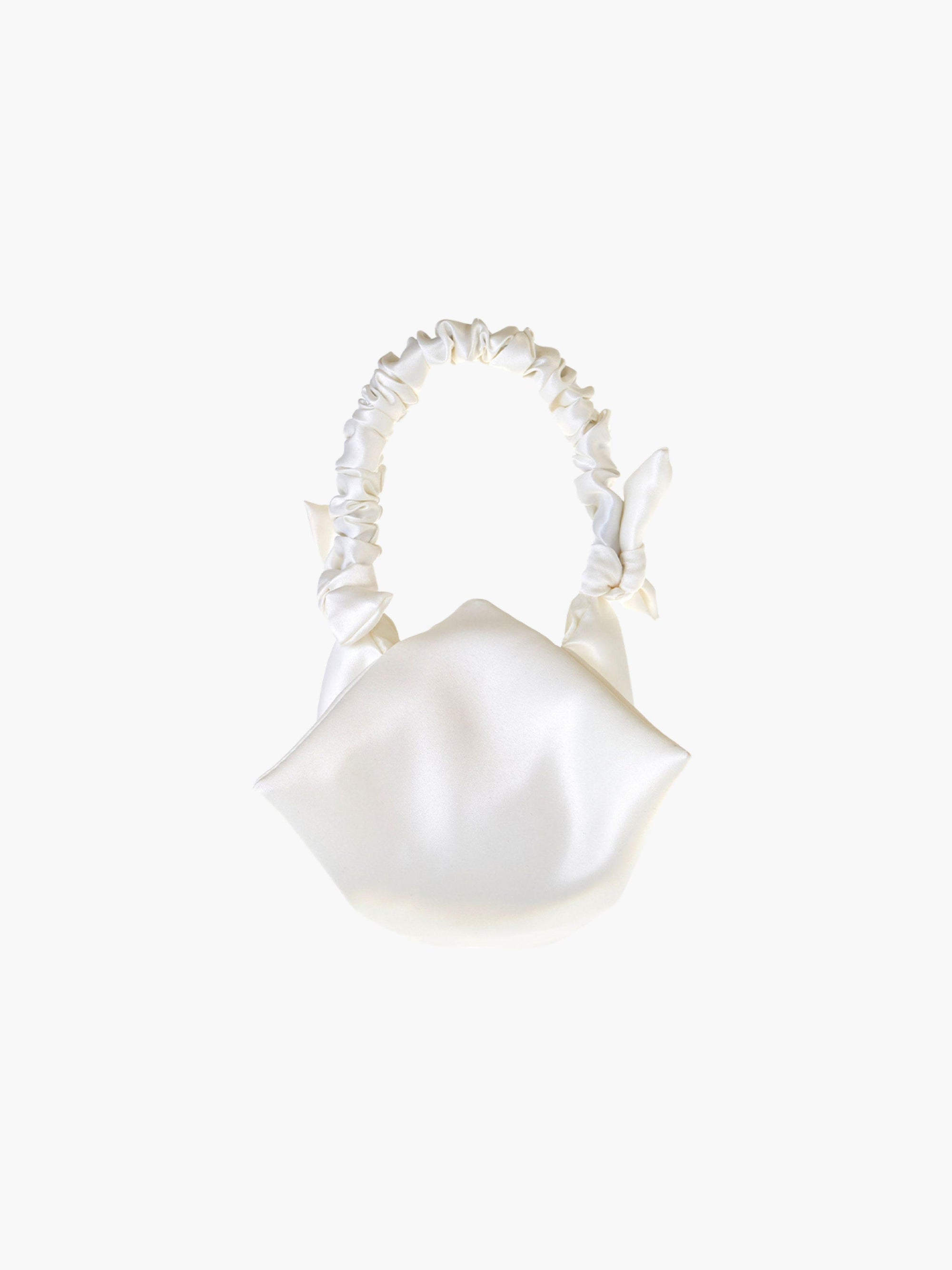 Ivory satin ruched handle handbag with decorative bows, set on a white background