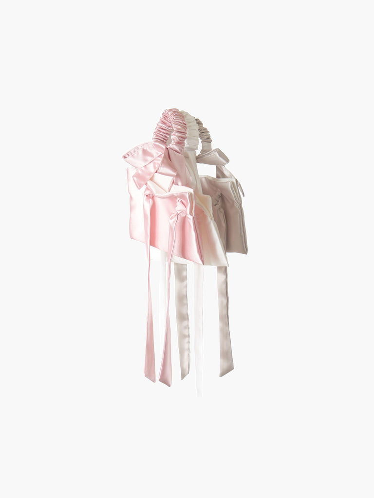 three satin wristlet bags in taupe, ivory and pink.