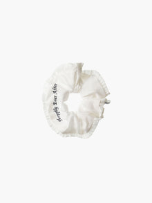 Ivory ruffled scrunchie with black embroidery that reads 'happily ever after' on a white background