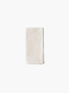 A folded cream-colored cloth napkin set against a plain white background. Simple and elegant.
