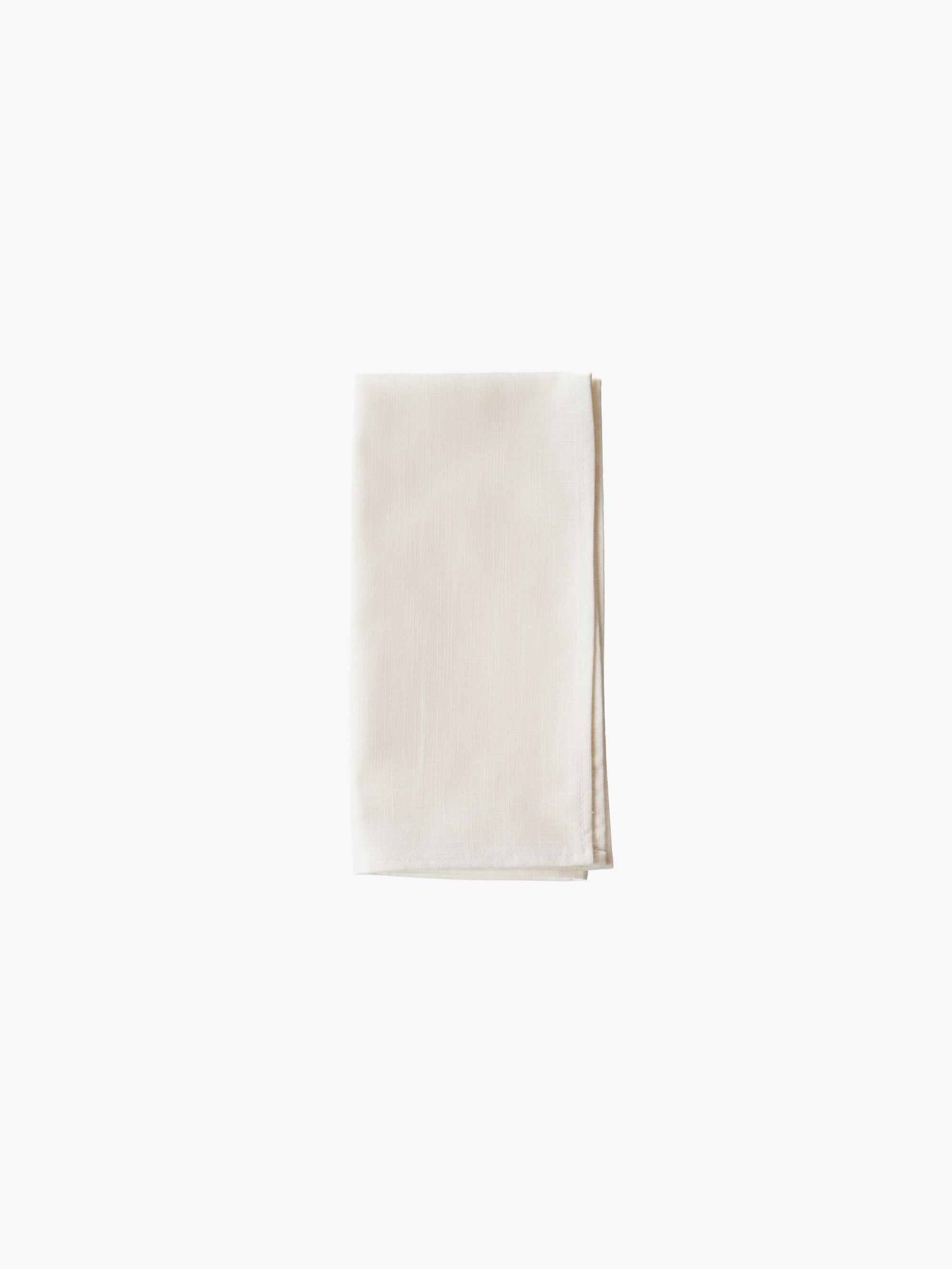 A folded cream-colored cloth napkin set against a plain white background. Simple and elegant.