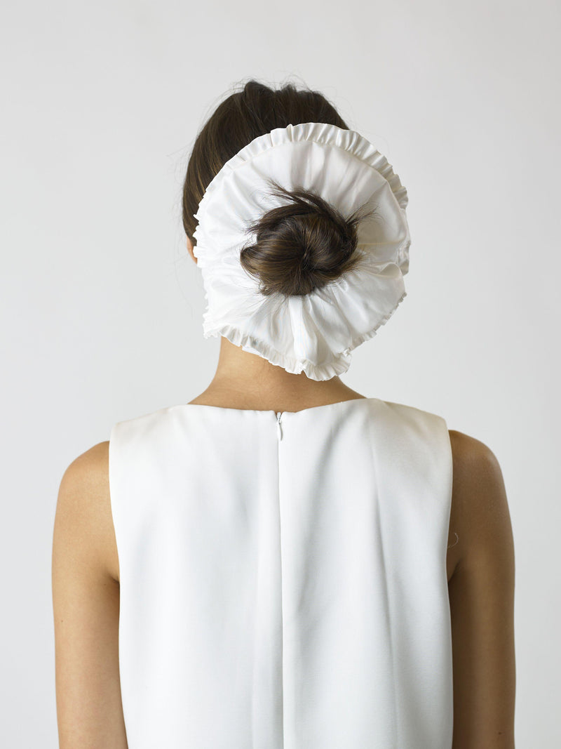 Person wearing an ivory large ruffled edge scrunchie over their bun, set against a plain background