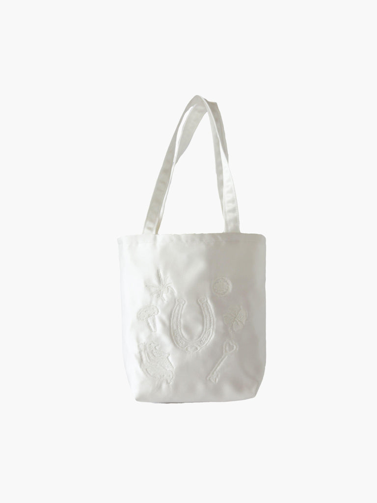 Ivory satin mini tote bag with good luck charms embroidered in ivory too. Set on a white background.