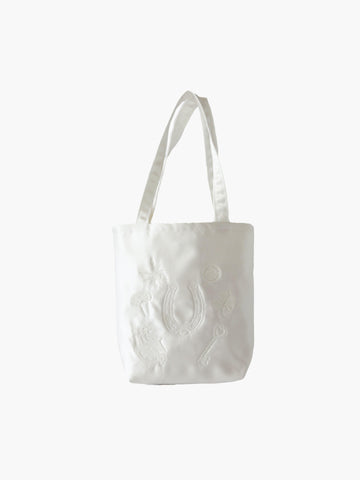Ivory satin mini tote bag with good luck charms embroidered in ivory too. Set on a white background.