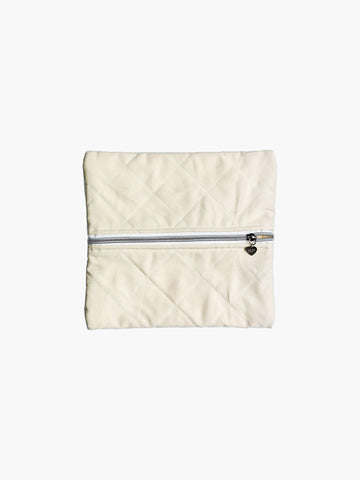A quilted ivory cotton zipper pouch, the zip has a heart charm on it. Set on a white background.