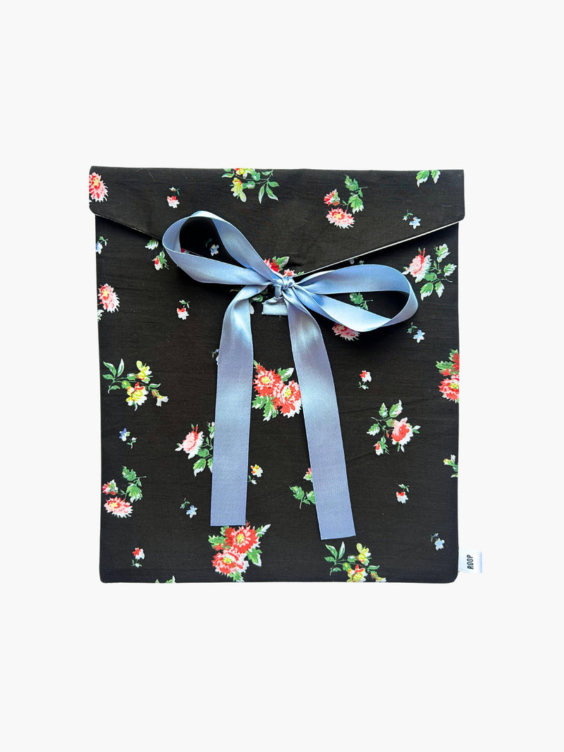 Black floral patterned fabric envelope pouch tied with a blue ribbon on a white background