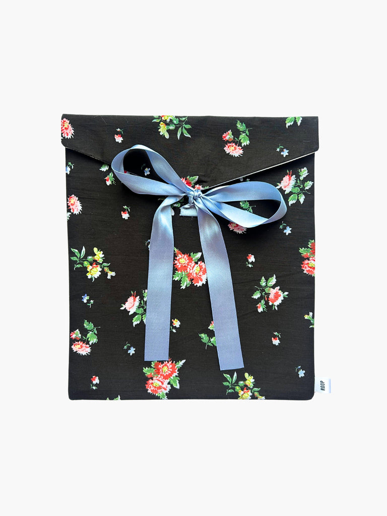 Black floral patterned fabric envelope pouch tied with a blue ribbon on a white background