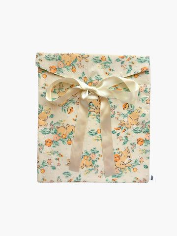 Floral and rabbit print fabric envelope gift pouch tied with an ivory ribbon. Set on a white background.