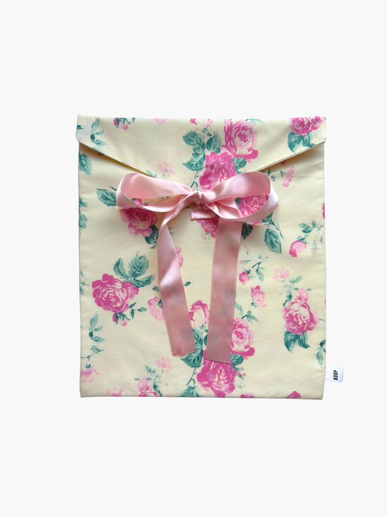 Cream and pink floral patterned fabric envelope pouch tied with a pink bow on a white background