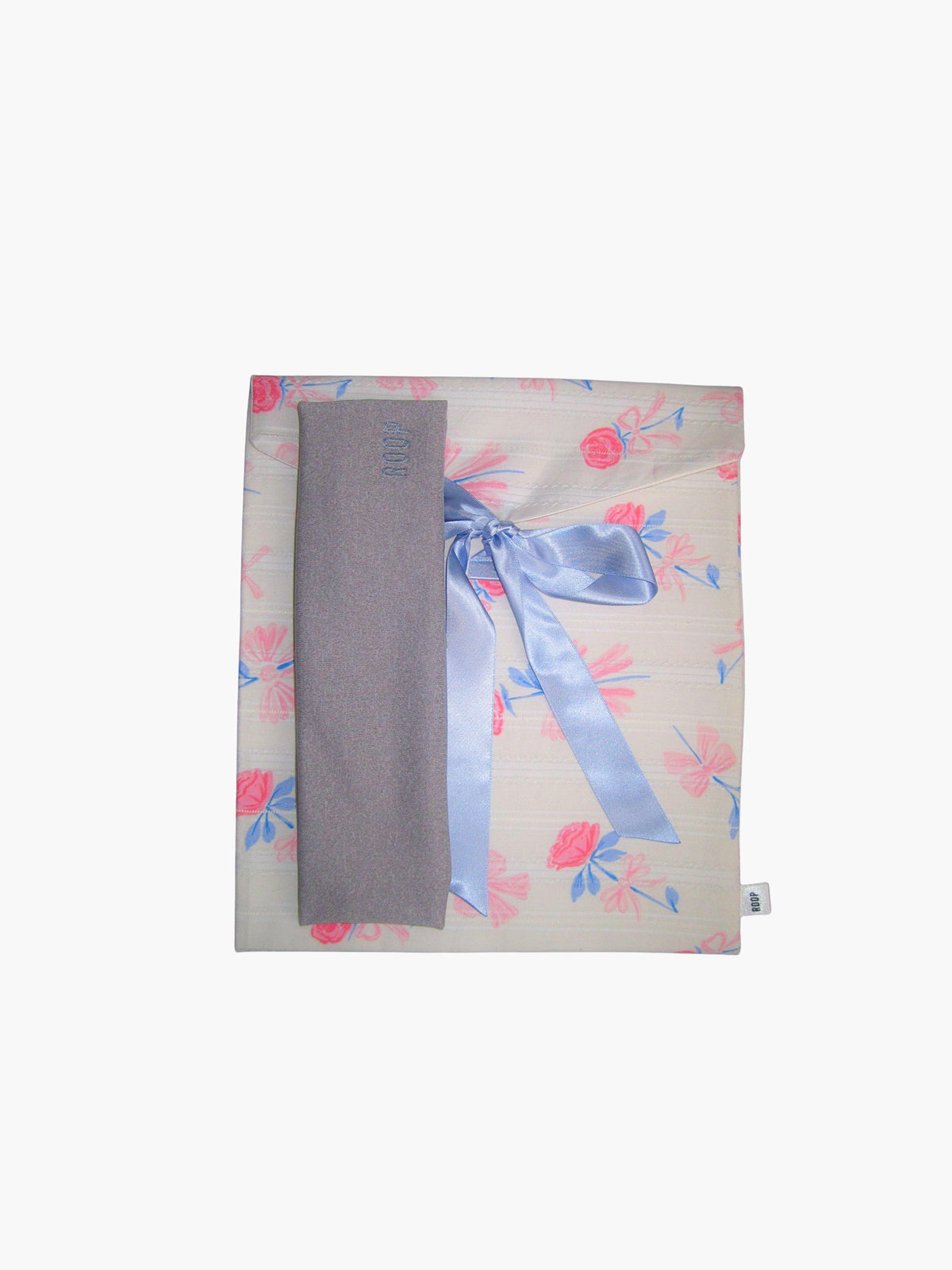 grey stretch headband, sat on top of a floral patterned ribbon tied fabric git pouch, set against a white background