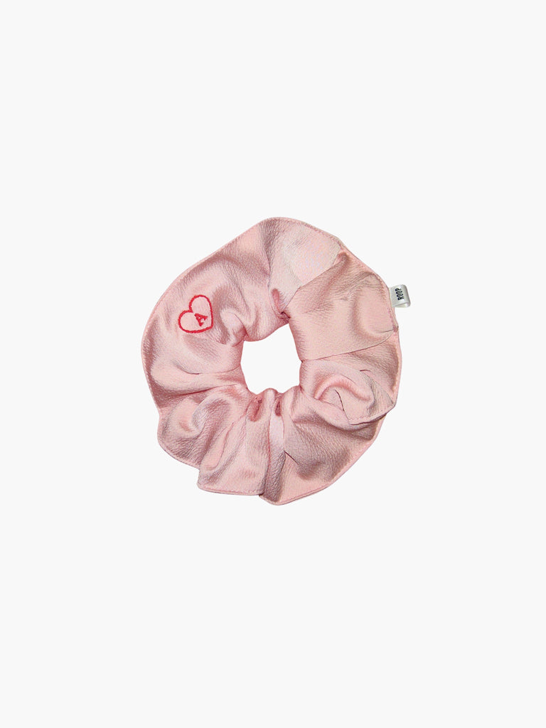Pink satin scrunchie embroidered with a red heart with the letter A inside, set on a white background