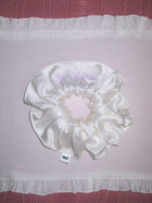 Ivory bamboo silk satin scrunchie with 'Just Married' embroidered in lilac on a white ruffled placemat, set on a pink moire  background.