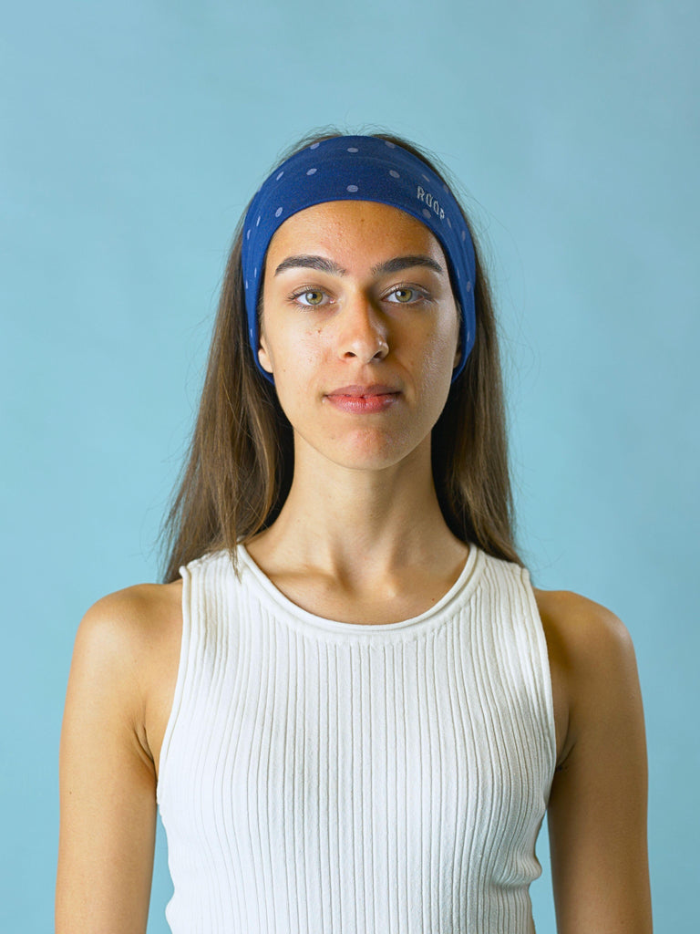 Woman wearing a blue headband with light blue polka dots a ROOP logo against a light blue background