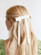 Woman with blonde hair styled with ivory bamboo silk satin hair bow clips against a light background